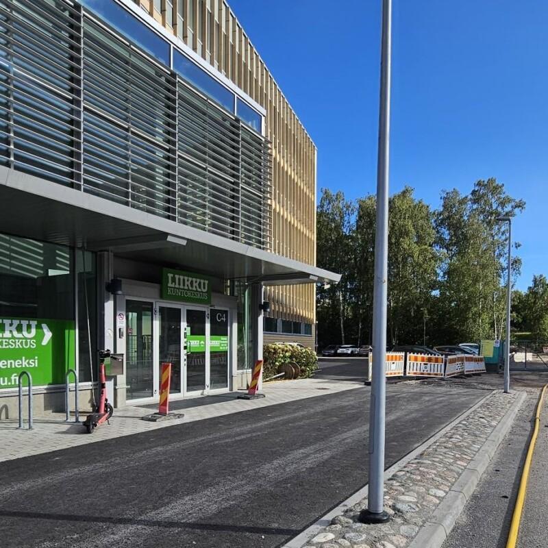 Kulku Niittykummun Liikkuun C4 ovesta. Parkkipaikat taustalla rakennuksen perällä.